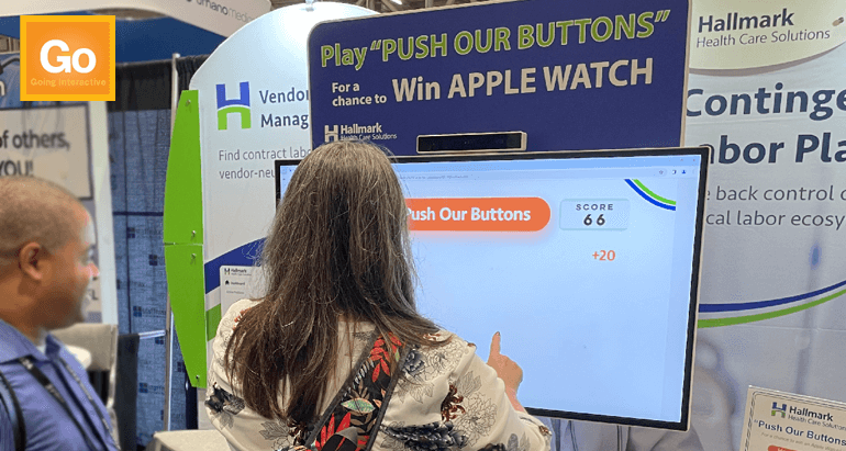 Person playing digital Whack-a-Mole game on touchscreen monitor in booth. 